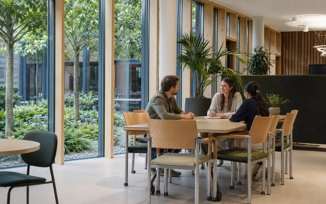 Ontmoetingsruimte met uitzicht op de binnentuin en natuurlijke materialen.